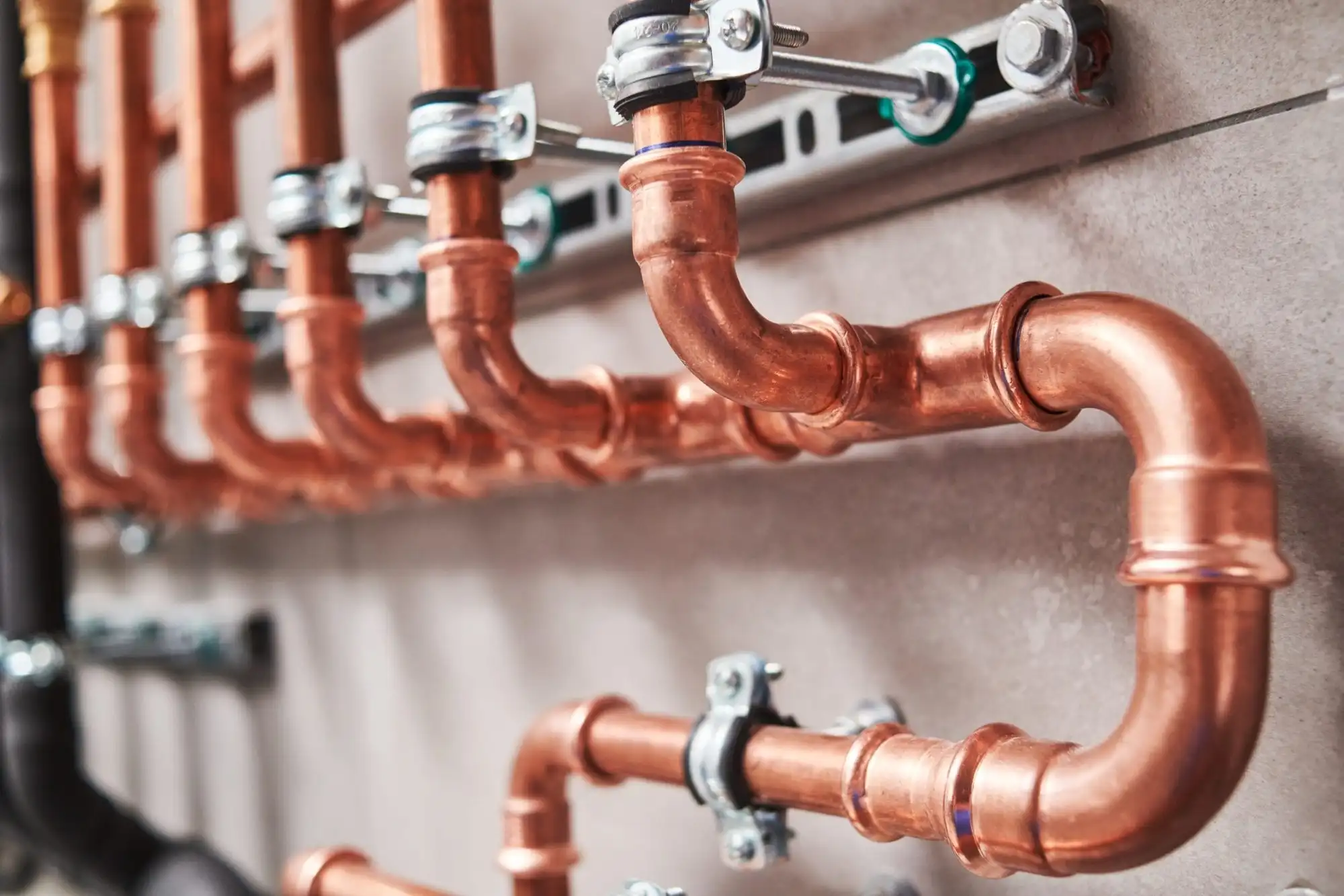 A run of copper supply lines press-fitted and clamped along a basement wall